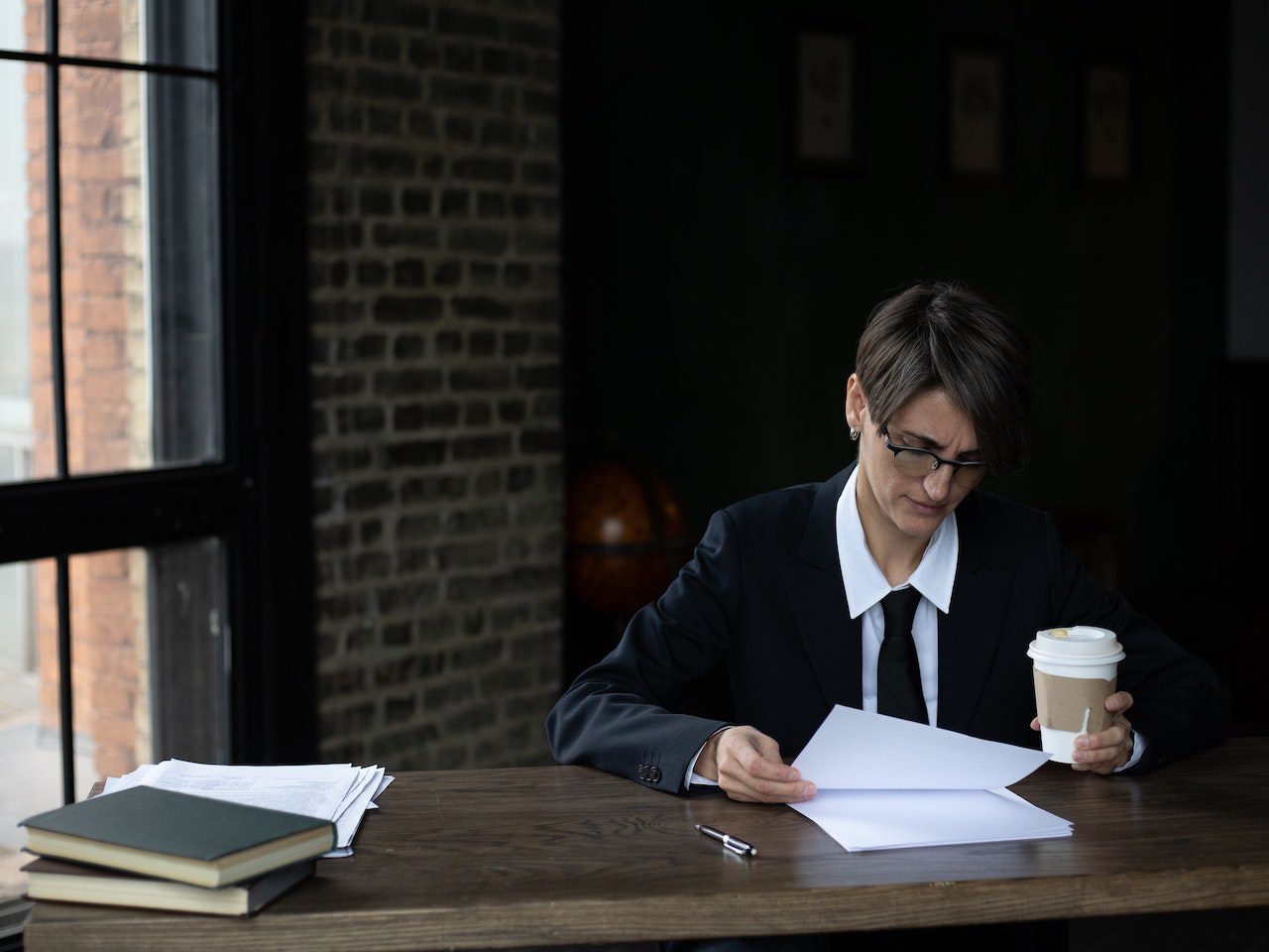 Woman in Black Blazer Reading While Holding a Disposable Cup